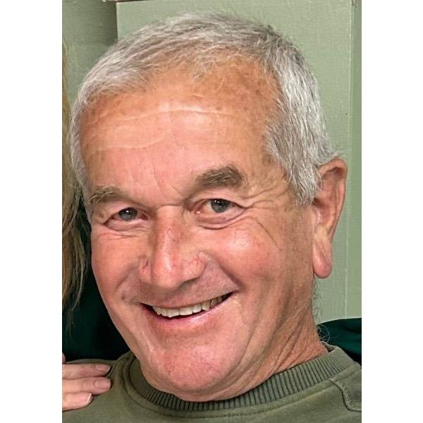 Older man with short gray hair smiling and wearing a green shirt.